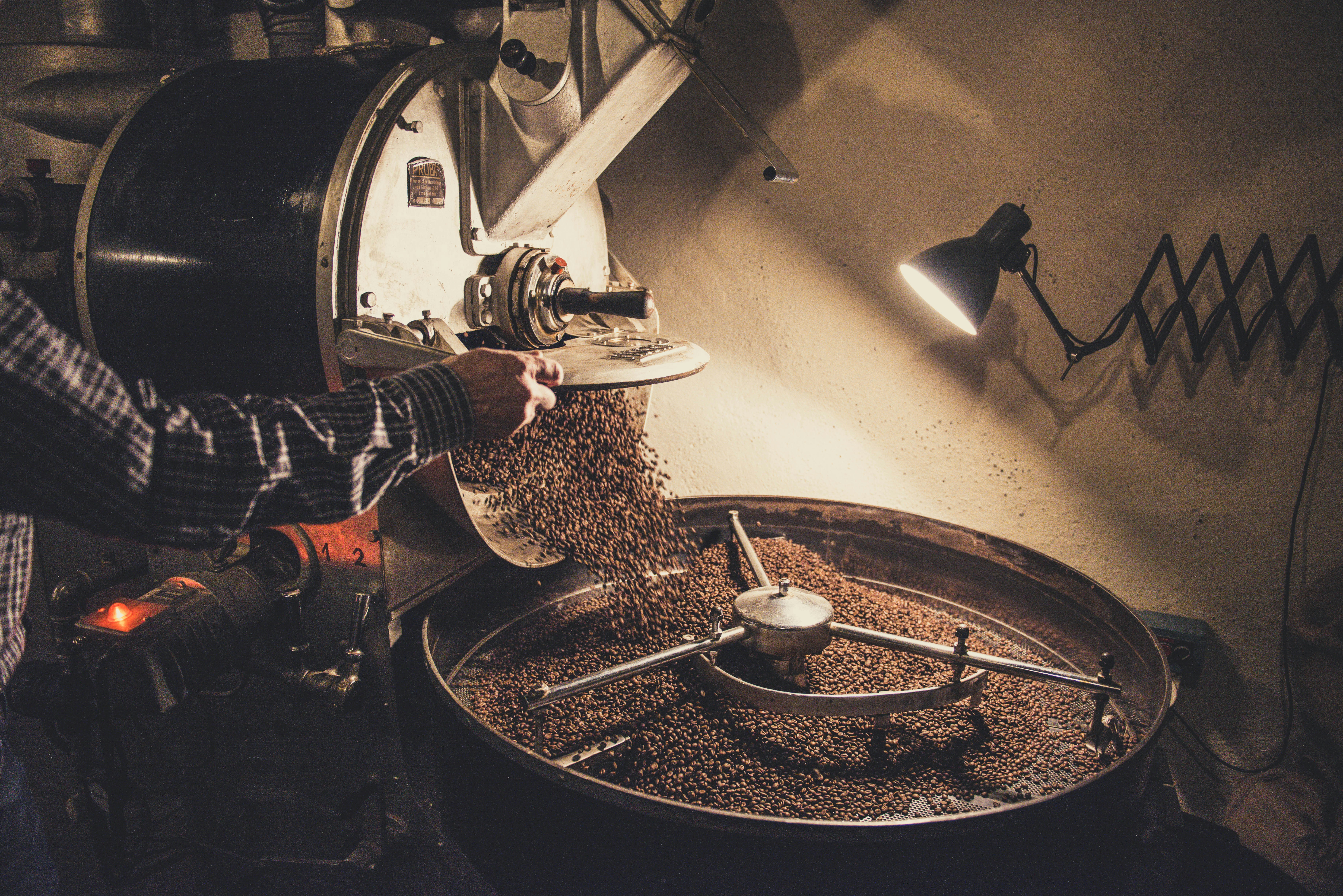 Persona che versa chicchi di caffè su una macchina
